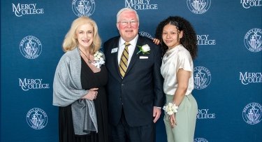 Mrs. Lee Nicholson Hall, President Tim Hall and Student Jade Alers pose in front of a step and repeat the event. 